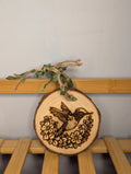Hand-burned pyrography of a hummingbird amongst flowers on a small natural round wood slice with twine and green ribbon hanger